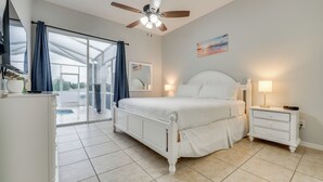 A bedroom with a large bed, a ceiling fan, a nightstand with a lamp, and a sliding glass door leading to a balcony. - Pool & Lanai: Davenport Home 12 Mi to Disney (Davenport)