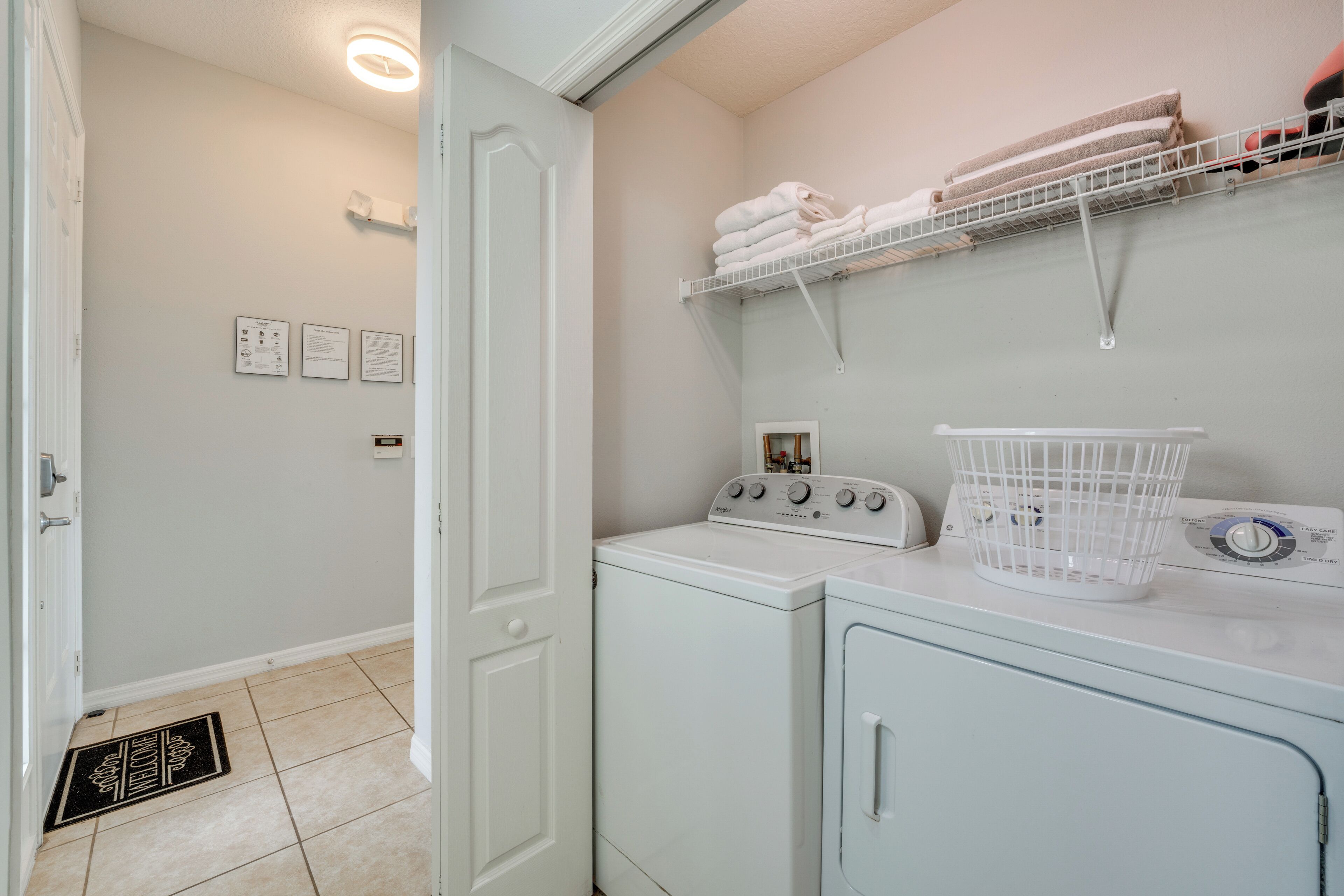 A laundry area with a washing machine, dryer, and stacked towels on a shelf.