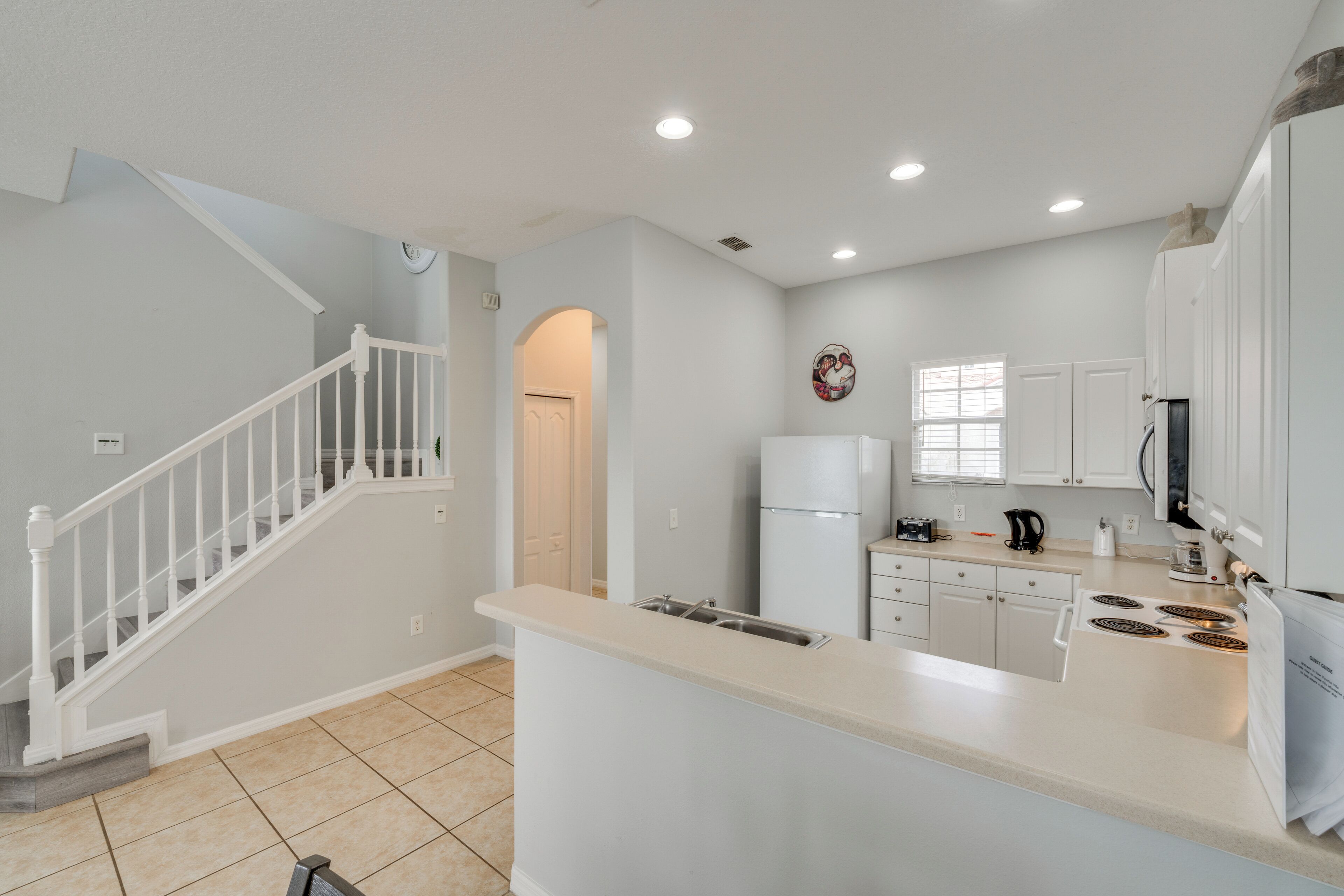 A modern kitchen with white cabinetry, a central island, and a built-in oven.