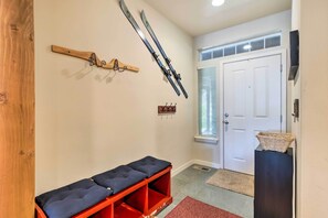 A hallway with a bench, skis on a wall-mounted rack, a door, and a basket on a stand. - Koul's Retreat' Condo 2 Mi to Lake Wenatchee (Leavenworth)