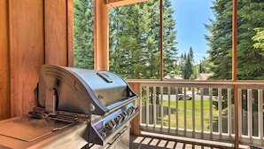 Ein Grill auf einem Balkon mit Blick auf eine grüne Landschaft und einen weißen Zaun.
