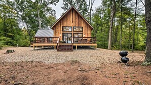 A wooden cabin with a deck, large windows, and a metal roof.