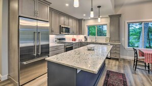 A modern kitchen with stainless steel appliances, granite countertops, and pendant lighting.