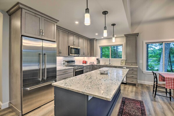 A modern kitchen with stainless steel appliances, a granite countertop, and pendant lighting.