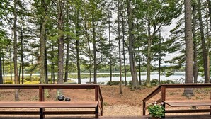 A wooden deck with benches overlooking a lake and forest.