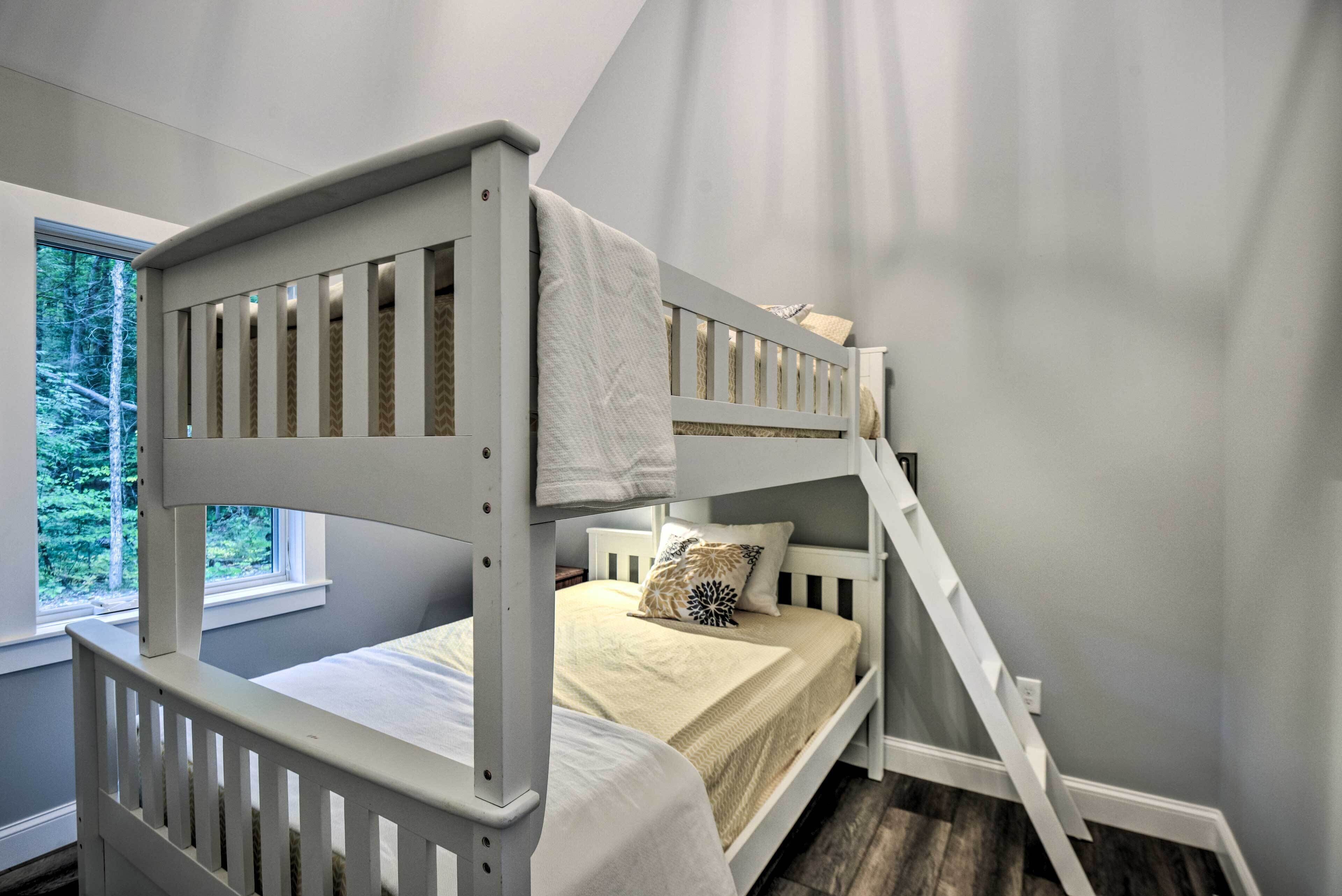 Un lit superposé avec une structure blanche et une fenêtre au-dessus.