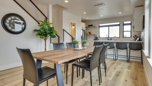 A modern kitchen with a wooden dining table, black chairs, and a potted plant. - Sleek Fraser Townhome < 8 Mi to Winter Park! (Fraser)