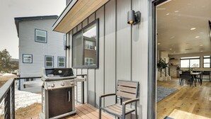 A patio with a grill, a chair, and a view of the house interior. - Sleek Fraser Townhome < 8 Mi to Winter Park! (Fraser)