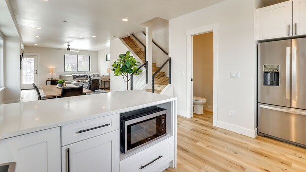 A modern kitchen with white cabinetry, a stainless steel refrigerator, and a built-in microwave. - Sleek Fraser Townhome < 8 Mi to Winter Park! (Fraser)