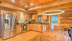 A modern kitchen with wooden cabinetry, stainless steel appliances, and a wooden dining table. - Riverfront Gold Bar Log Cabin Near Stevens Pass! (Gold Bar)