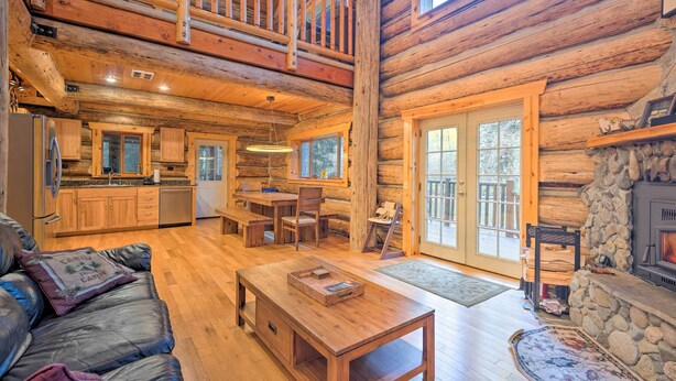 A log cabin interior with a dining area, kitchen, and a fireplace. - Riverfront Gold Bar Log Cabin Near Stevens Pass! (Gold Bar)