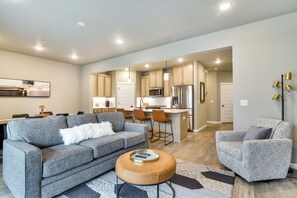A modern living room with a grey sofa, a coffee table, and a patterned armchair. - Elegant Vancouver Townhome - 18 Mi to Portland (Vancouver)