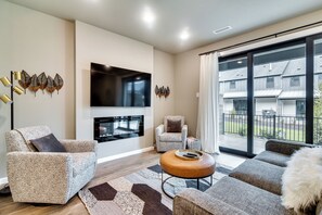 A modern living room with a fireplace, comfortable seating, and a large window offering a view of the outside. - Elegant Vancouver Townhome - 18 Mi to Portland (Vancouver)