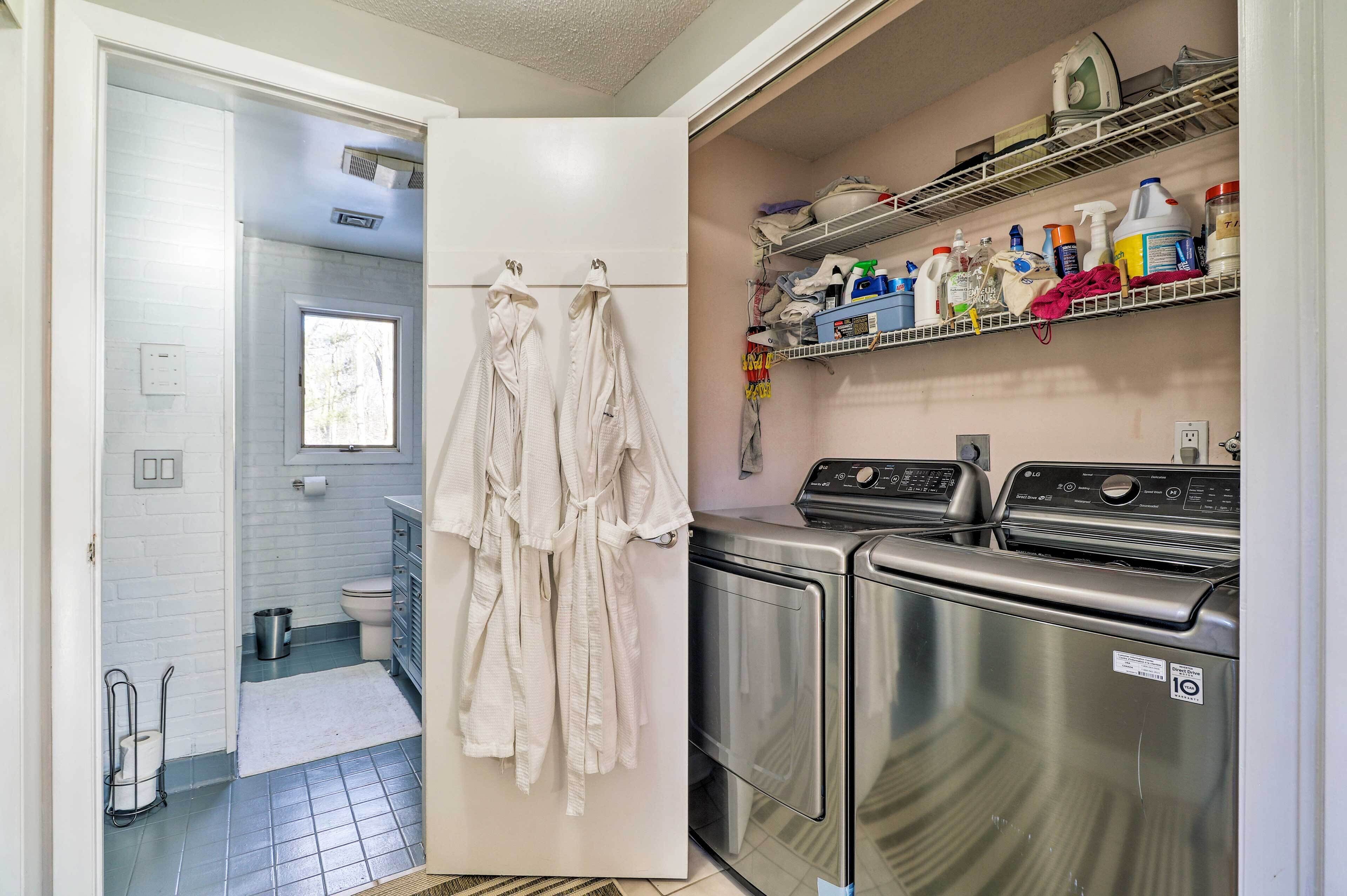 A laundry room with a washing machine, dryer, and shelves with cleaning supplies.