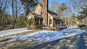 A cabin with a prominent chimney, surrounded by trees and a snow-covered ground. - Peaceful Goshen Cottage w/ Screened Porch & Views! (Goshen)