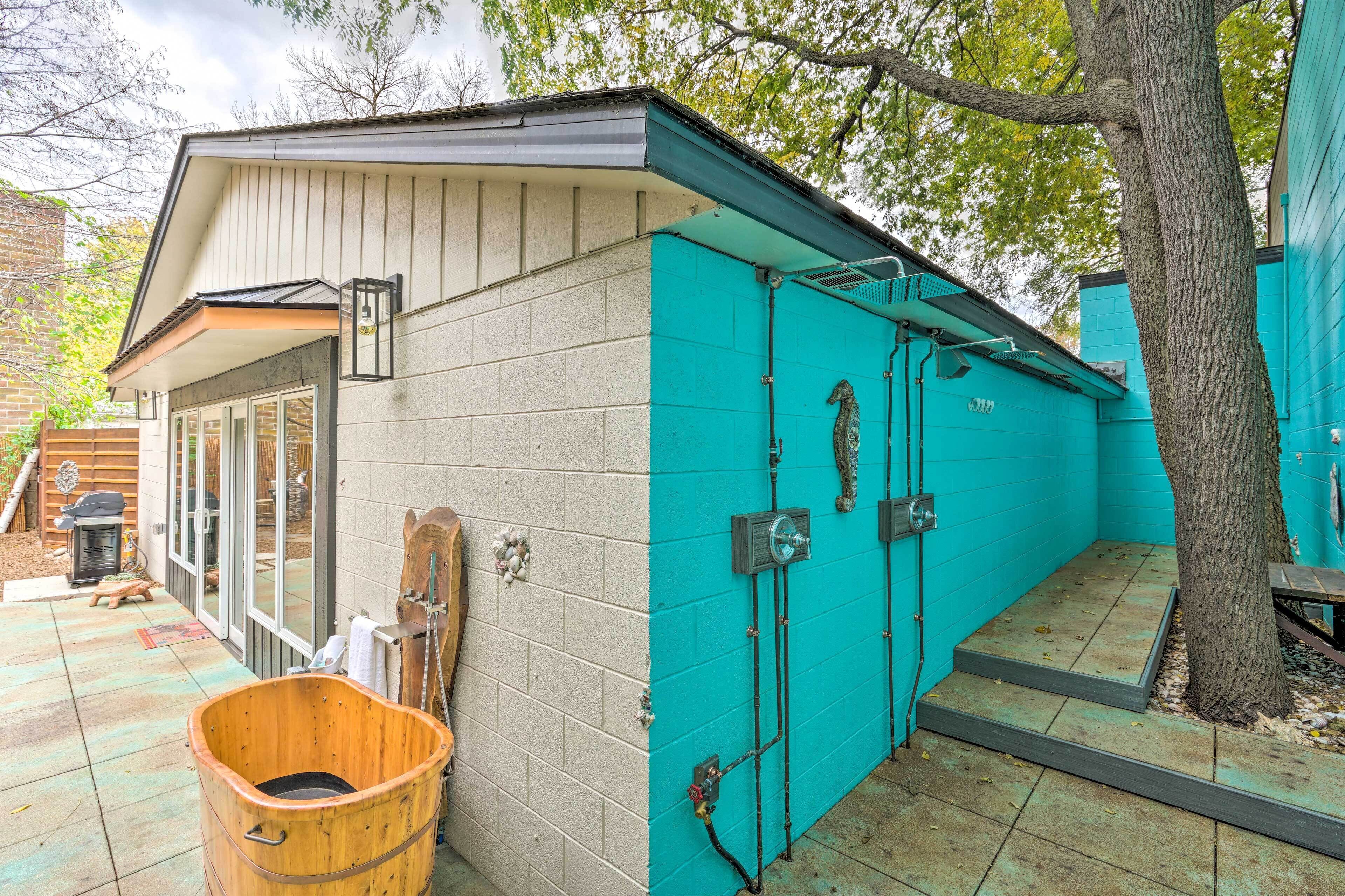 A building with a teal exterior, a wooden bucket, and a tree.