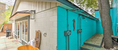 A building with a teal exterior, a wooden bucket, and a tree.