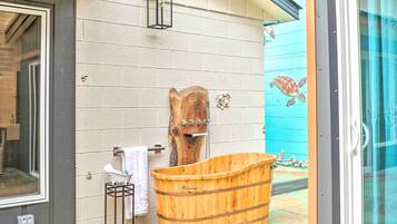 A wooden bathtub and a wooden sculpture against a wall.