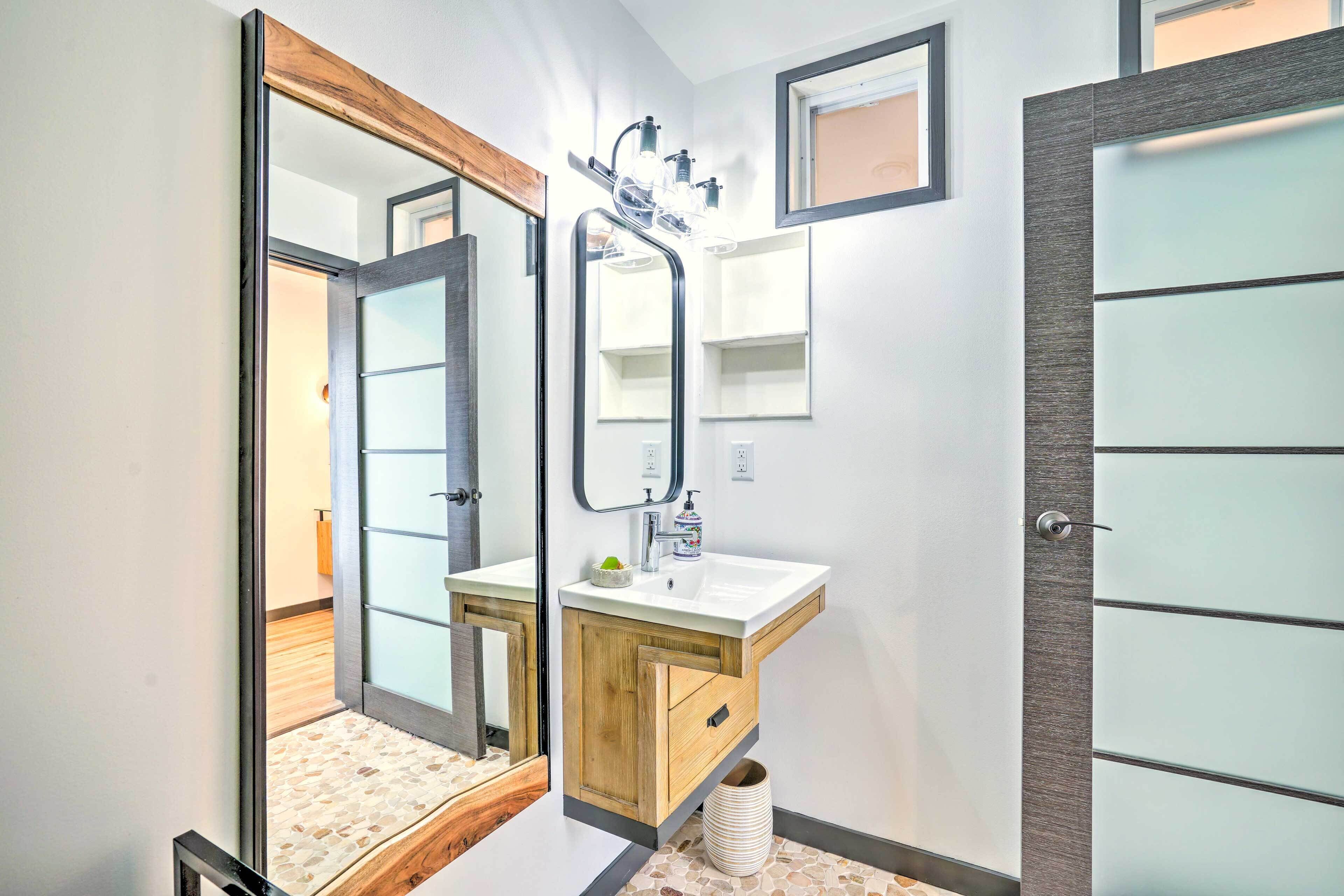 A modern bathroom with a wooden vanity, a large mirror, and a glass shower enclosure.