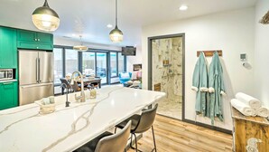 Een moderne keuken met een groot eiland, groene kasten en uitzicht op de eetruimte.