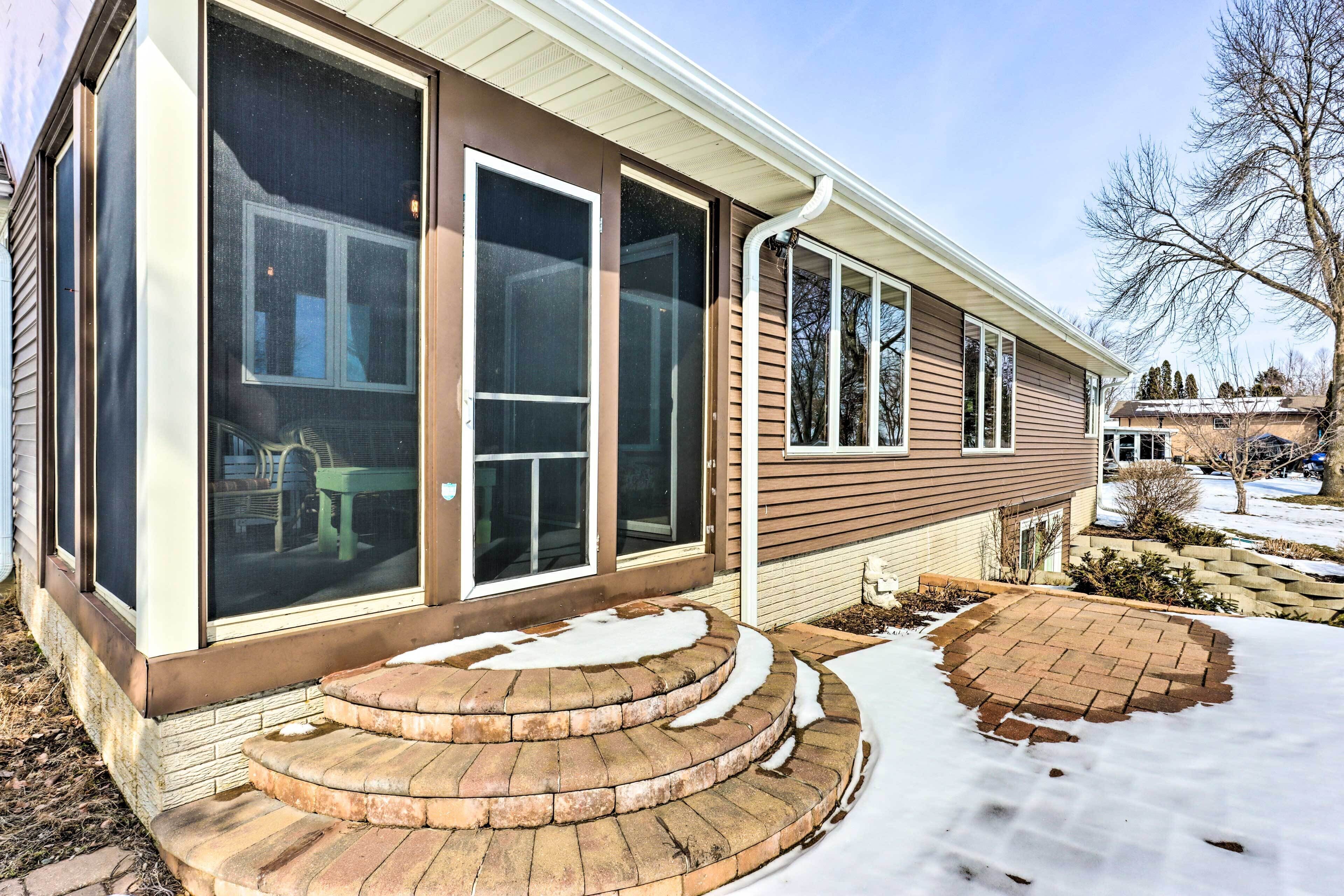 A two-story house with a covered porch, a brick entryway, and a snow-covered yard.