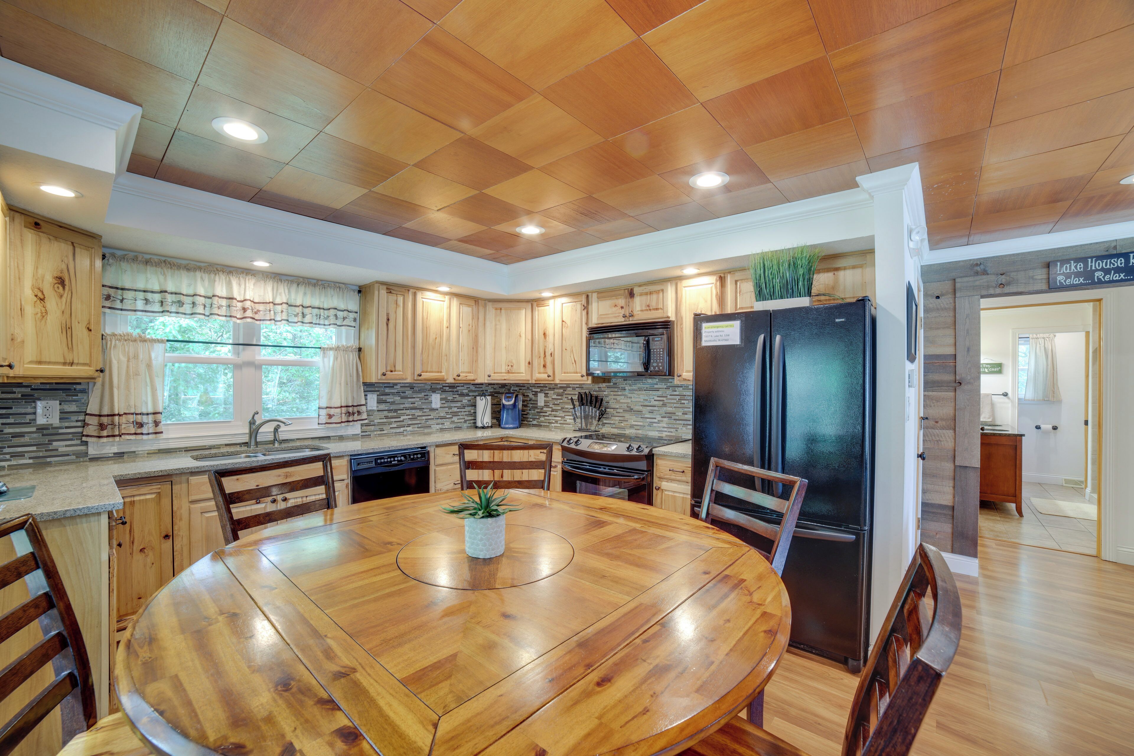 A modern kitchen with wooden cabinets, a central island, and a built-in microwave.