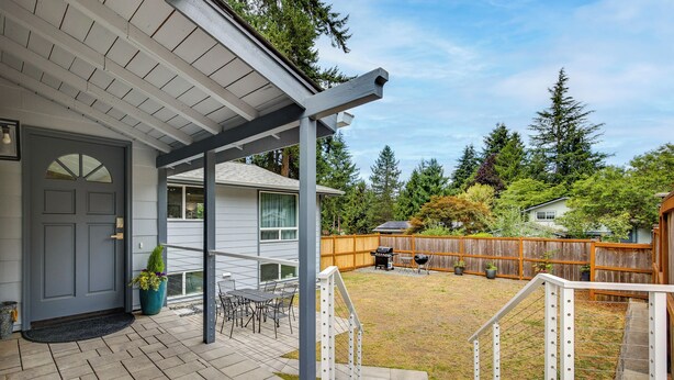 A covered patio with a table and chairs, a wooden fence, and a grassy yard. - Redmond Retreat w/ Fenced Yard & EV Charger (Redmond)