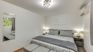A bedroom with a bed, bedside lamps, a mirror, a wall art piece, and a window with curtains. - Redmond Retreat w/ Fenced Yard & EV Charger (Redmond)