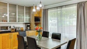 A modern kitchen with a dining area, including a table with chairs, a microwave, a toaster, and a vase with flowers. - Redmond Retreat w/ Fenced Yard & EV Charger (Redmond)