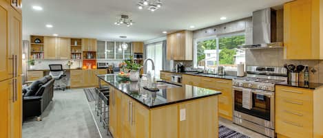 A modern kitchen with a central island, stainless steel appliances, and wooden cabinetry.