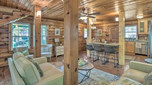 L’intérieur d’une cabane en rondins comprend un coin repas, une cuisine et un espace détente avec vue sur l’extérieur.