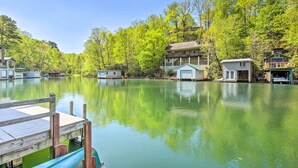 Un chalet au bord du lac, doté d’un quai, entouré d’une forêt dense et dont l’image se reflète dans les bâtiments environnants.