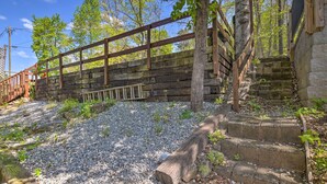 Un pont en bois rustique enjambe un chemin de gravier menant à un escalier en pierre.