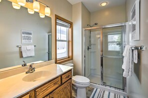 A bathroom with a large mirror, a sink, a toilet, and a glass-enclosed shower. - Stunning Waterville Home on Tetonka Lake! (Waterville)