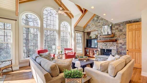 A spacious living room with a stone fireplace, large windows, and a cozy seating area.