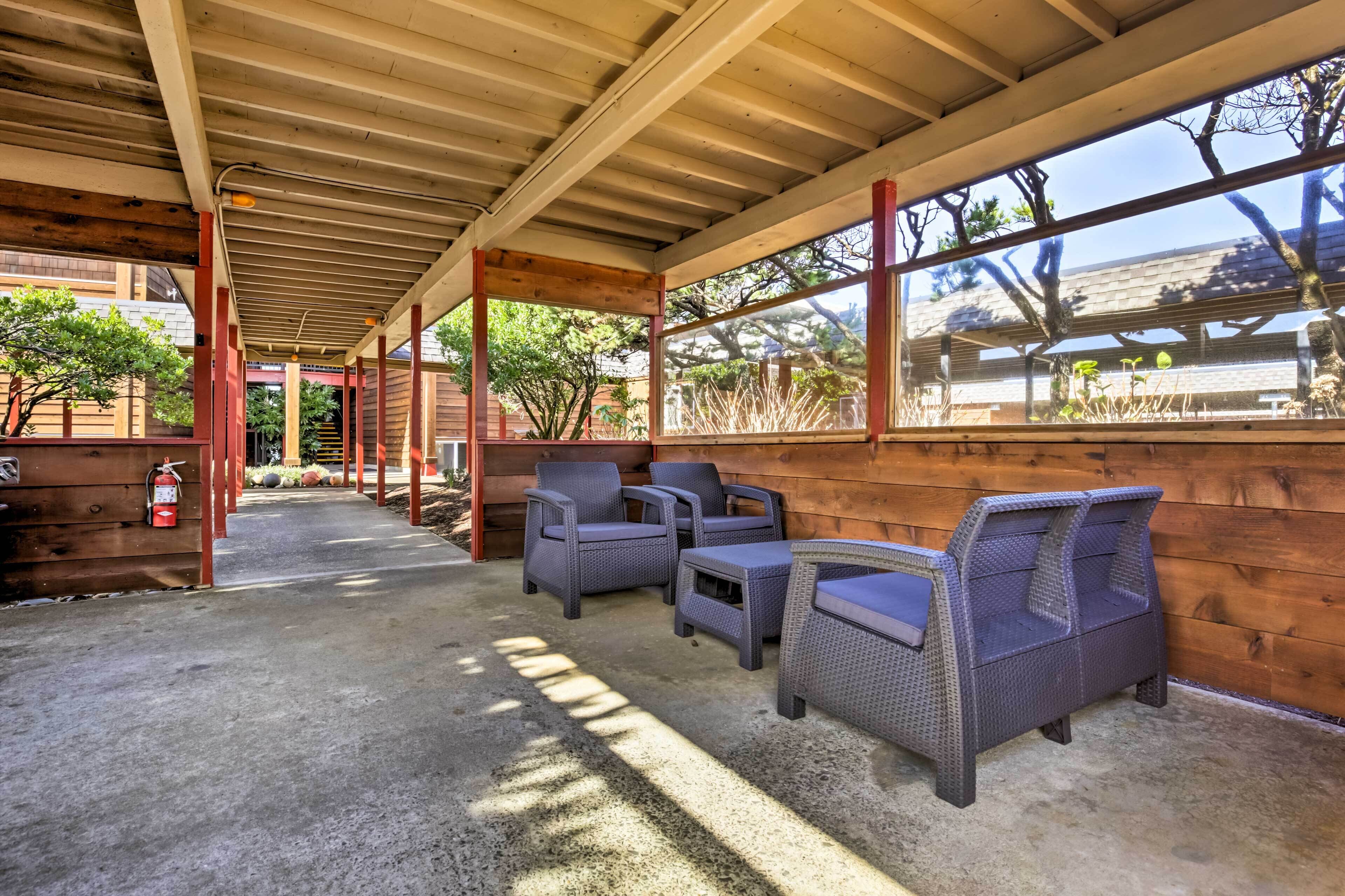 A covered outdoor seating area with wicker furniture and a fire extinguisher.