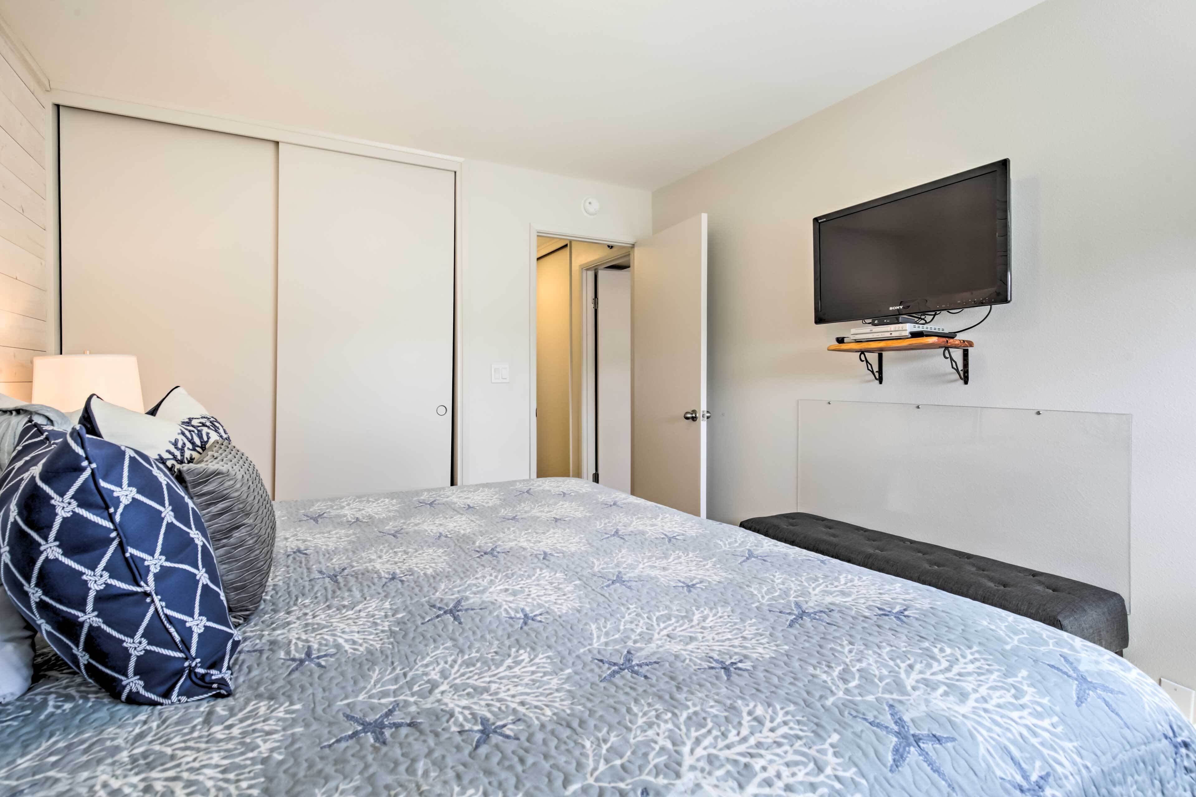 Ein Schlafzimmer mit einem Bett, einem an der Wand befestigten Fernseher und einem Kleiderschrank.