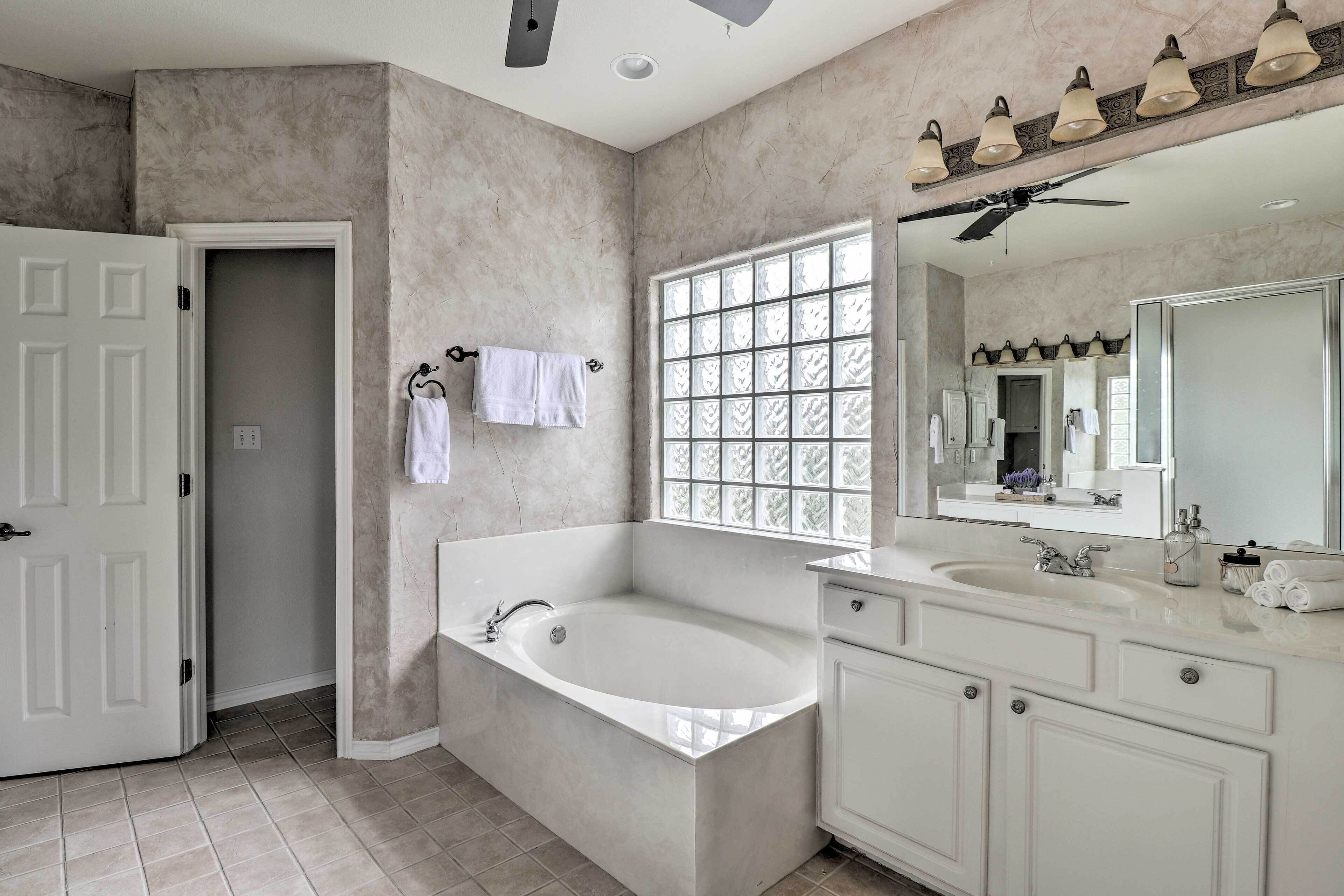 A modern bathroom with a freestanding bathtub, a large mirror, and a vanity with a sink.