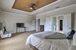 Een slaapkamer met een bed, een televisie, een stoel en een plafondventilator.