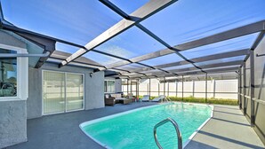 An indoor swimming pool with a glass ceiling, lounge chairs, and a view of the backyard. - Port Richey Getaway w/ Lanai, Pool & Grill! (New Port Richey)