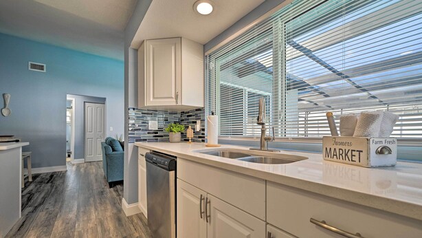 A modern kitchen with white cabinets, a dishwasher, and a countertop with a sign reading "Farm Fresh MARKET". - Port Richey Getaway w/ Lanai, Pool & Grill! (New Port Richey)