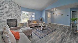 A living room with a fireplace, a sofa, a coffee table, and a rug. - Port Richey Getaway w/ Lanai, Pool & Grill! (New Port Richey)