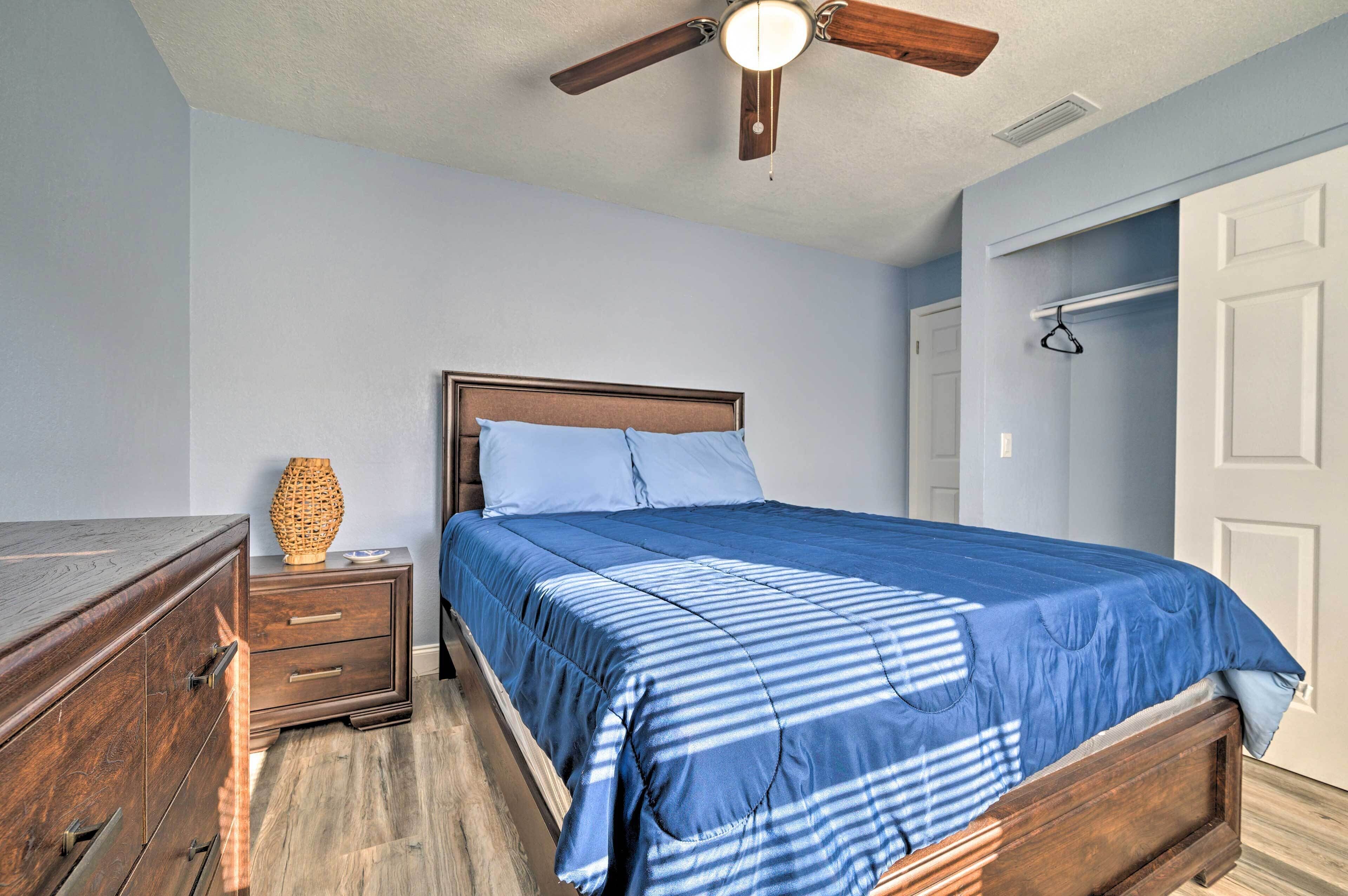 A bedroom with a bed, wooden nightstand, dresser, and a ceiling fan.