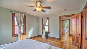 A bedroom with a bed, wooden floor, ceiling fan, and a view of another room through an open door. - Front Royal Retreat ~ 1 Mi to National Park! (Front Royal)