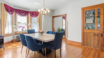A dining area with a marble table, blue upholstered chairs, and a chandelier.