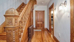 A wooden staircase with intricate carvings, a wooden door, and wall sconces. - Front Royal Retreat ~ 1 Mi to National Park! (Front Royal)