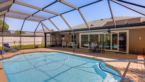 A swimming pool with a glass enclosure, a patio area with chairs, and a view of the backyard. - Saltwater Pool! Sebring Oasis Near Lake Jackson (Sebring)