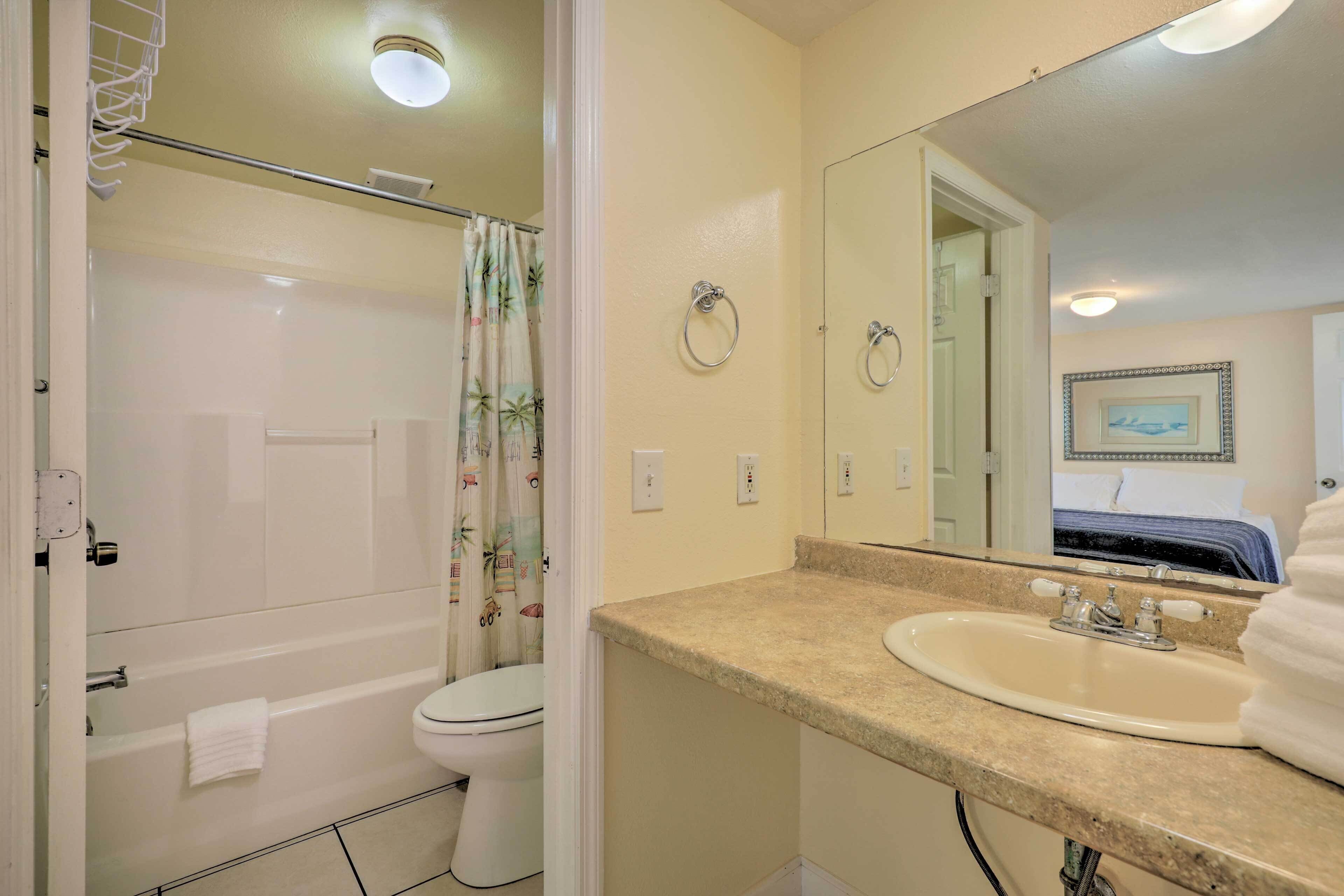 A bathroom with a bathtub, toilet, sink, and a mirror.