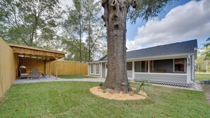 Una casa con porche cubierto, un árbol grande y césped.