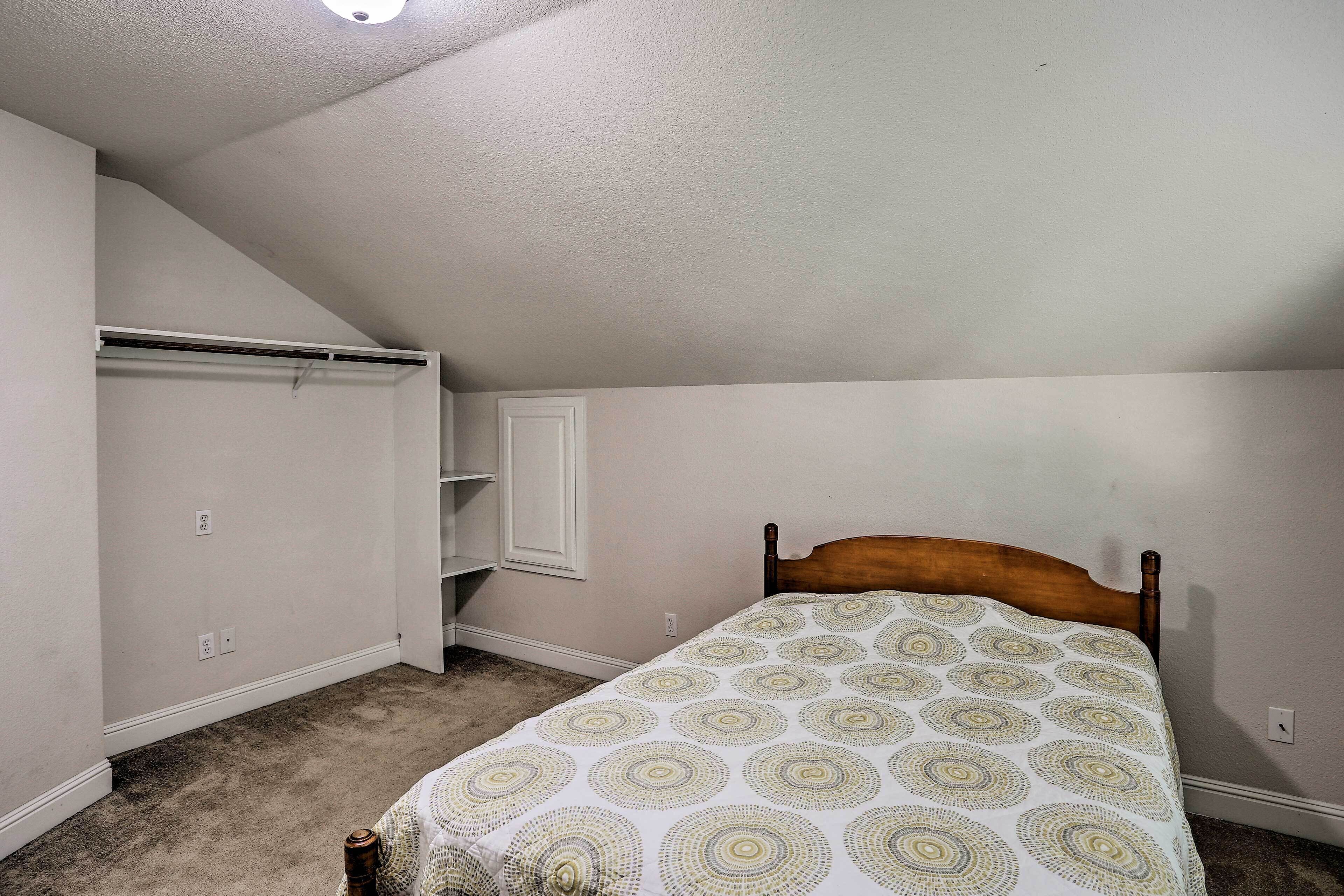 A bedroom with a bed, a closet, and a slanted ceiling.